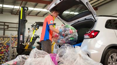 Unloading bags of recyclable material from a car.