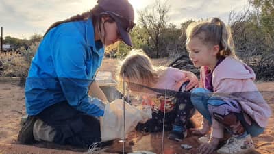 Volunteer Tamara Potter showing Ellie and Isla animals in a pitfall trap.