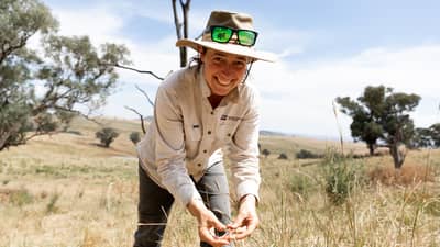 Ecologist Imogen Semmler happily inspecting grasses on a farm.
