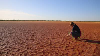 Greg Sousaari surveys an area of dry, cracked mud.