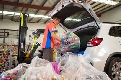 Unloading bags of recyclable material from a car.