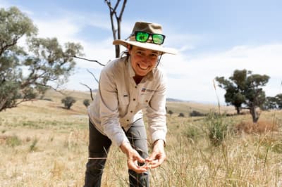 Ecologist Imogen Semmler happily inspecting grasses on a farm.