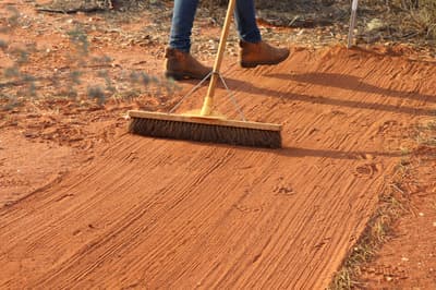 A broom sweeping a sand pad for monitoring animal tracks.