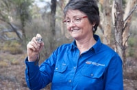 Bush Heritage Ecologist Angela Sanders smiles down at a Red-tailed Phascogale, a small, mouse-like mammal, she is holding in one hand.