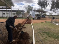 Digging a trench to connect the homestead gutters.