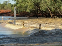 Flood markers show the depth of water rushing over the road.