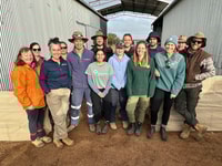 Fourteen people, a mix of Bush Heritage and Carbon Positive Australia staff and volunteers, gather in front of corrugated iron sheds at Eurardy Reserve.
