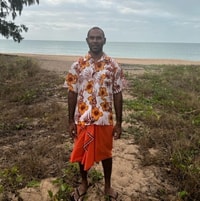 Torres Strait Islander man Naizel Enosa, a dark-brown-skinned man wearing a floral shirt and sarong.