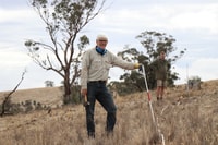 Bush Heritage volunteer Garry McDonald, an older man, hammering in posts at Nardoo Hills Reserve.