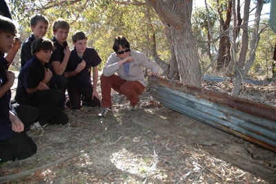 Ecologist showing school group some ideal lizard habitat.