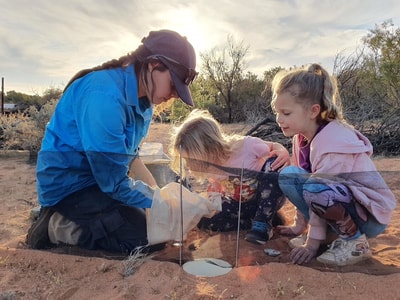 Volunteer Tamara Potter showing Ellie and Isla animals in a pitfall trap.
