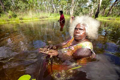 Mary Kolkiwarra in a water hole with handful of berries.